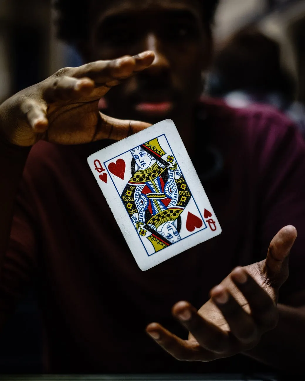 Figure with Queen of Hearts card floating in between their hands